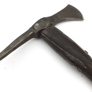 May include: A black metal axe with a wooden handle. The axe has a sharp blade and a pointed pick on the opposite side. The axe is a historical weapon and tool.