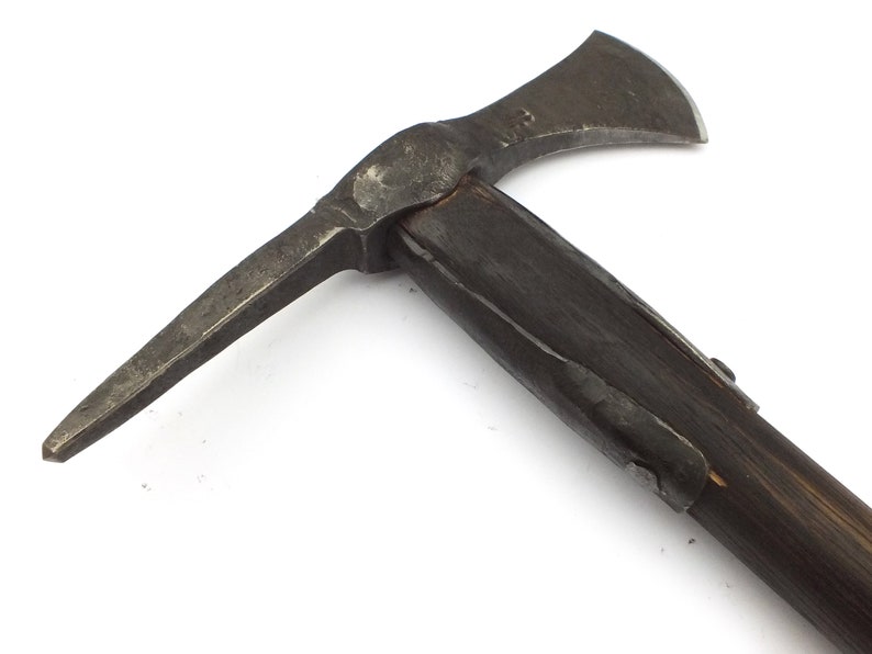 May include: A black metal axe with a wooden handle. The axe has a sharp blade and a pointed pick on the opposite side. The axe is a historical weapon and tool.