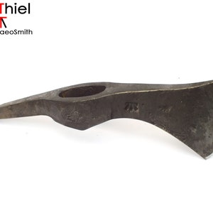 Op de afbeelding: Een handgesmeed stalen tomahawk met een enkelzijdige kling en een gat in de kop voor een handvat. De tomahawk heeft een donkergrijze afwerking en een licht gebogen kling.