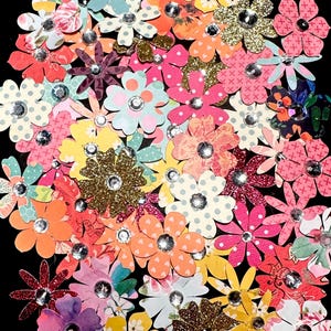 May include: Assortment of colorful paper flowers with glitter and rhinestones. The flowers are in various shades of pink, red, yellow, blue, and green.