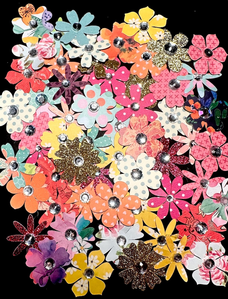 May include: Assortment of colorful paper flowers with glitter and rhinestones. The flowers are in various shades of pink, red, yellow, blue, and green.