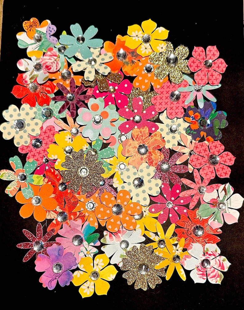 May include: A collection of colorful paper flowers with glitter and rhinestones. The flowers are arranged in a cluster and have a variety of patterns and designs.
