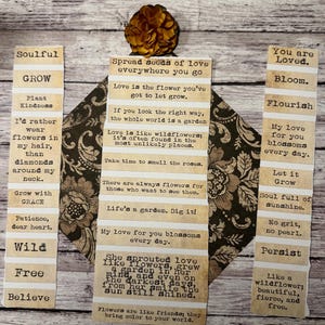 Puede incluir: Un collage decorativo con citas inspiradoras impresas en tiras de papel, dispuestas alrededor de una pieza central estampada. Las citas est&aacute;n en una fuente de m&aacute;quina de escribir, con una flor seca en la parte superior. El tema es el amor, el crecimiento y la naturaleza.