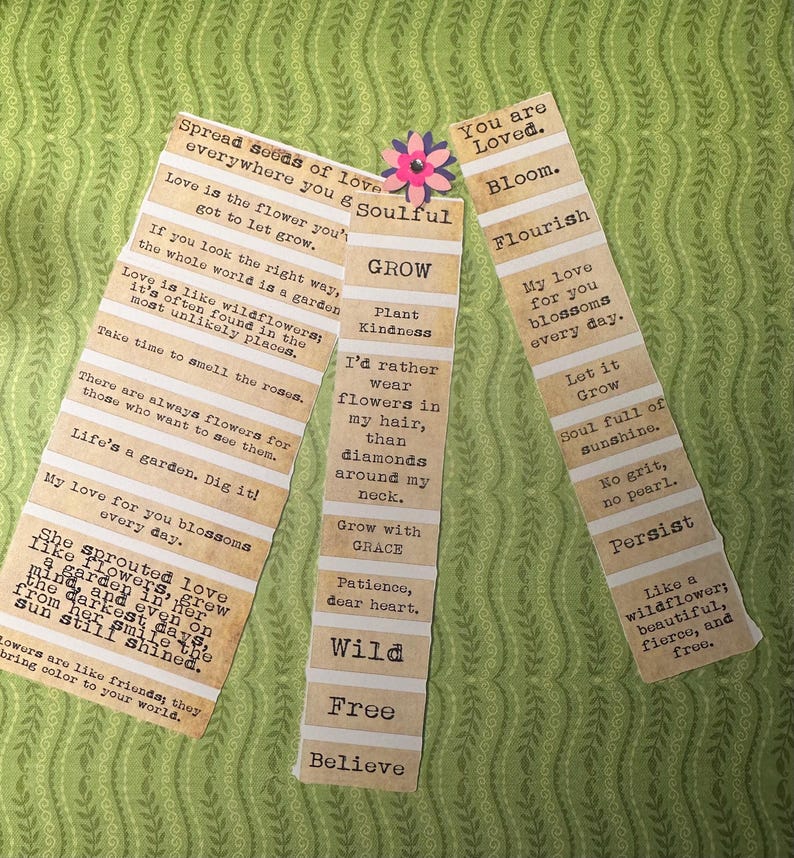 Puede incluir: Tres marcap&aacute;ginas de papel con citas inspiradoras. Los marcap&aacute;ginas tienen una est&eacute;tica vintage con un dise&ntilde;o a rayas beige y blanco. Una peque&ntilde;a flor de papel est&aacute; unida a un marcap&aacute;ginas. El fondo es un estampado floral verde.