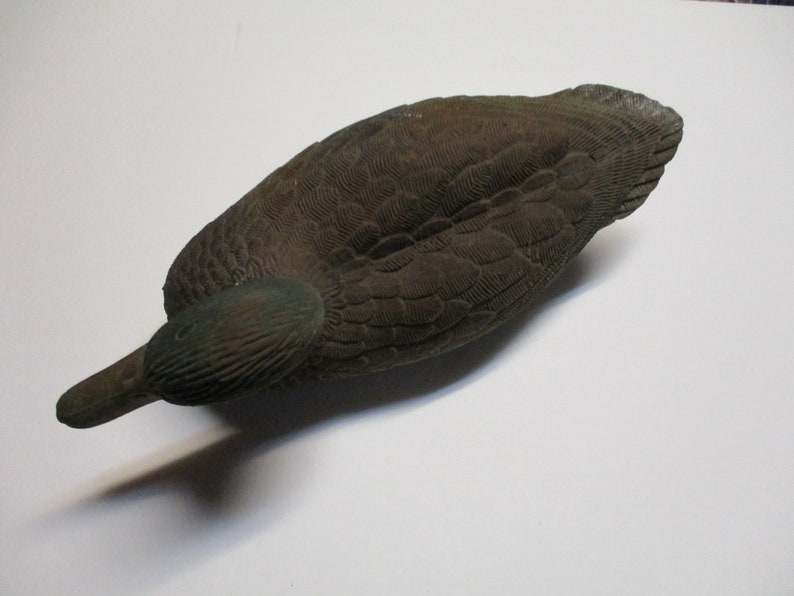 Puede incluir: Un se&ntilde;uelo de pato marr&oacute;n con marcas de plumas detalladas. El se&ntilde;uelo est&aacute; hecho de un material duro y tiene un aspecto realista.
