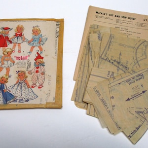 May include: Vintage McCall's doll clothes sewing pattern set. The pattern envelope features illustrations of dolls in various outfits. Includes pattern pieces and a "Cut and Sew Guide".