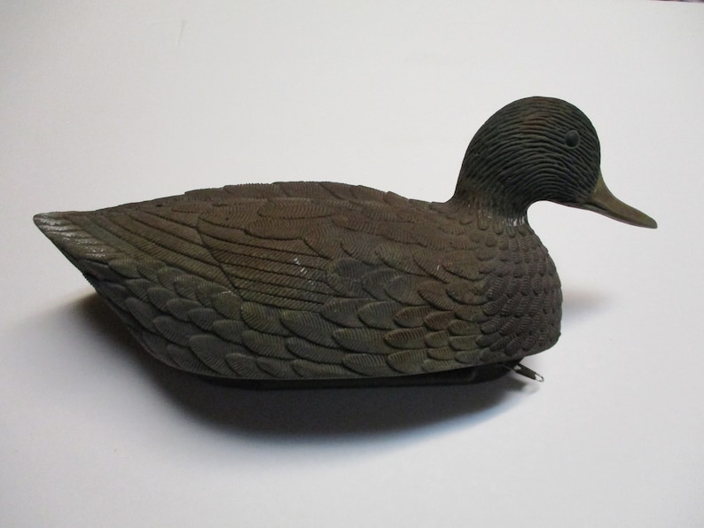 Puede incluir: Un se&ntilde;uelo de pato de pl&aacute;stico marr&oacute;n y negro con marcas de plumas detalladas. El se&ntilde;uelo est&aacute; dise&ntilde;ado para parecerse a un pato real y se utiliza para la caza.