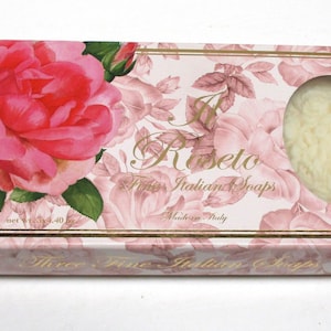 May include: A rectangular box of Roseto Italian soaps. The box is decorated with a pink floral pattern and a large pink rose. A single oval soap is visible through a window.