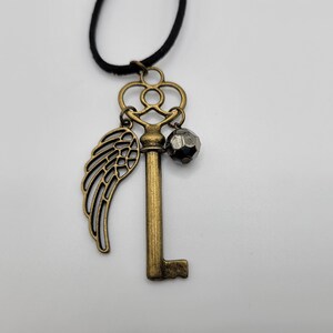 Bronze key pendant necklace | filigree wing | shiny black bead | suede cording | key to my heart | boho jewelry | brass skeleton key | fly