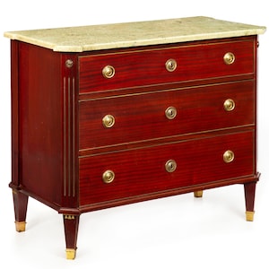 May include: A mahogany chest of drawers featuring three horizontal drawers with circular brass pulls and central keyholes. The piece is topped with a light-colored, speckled stone slab and stands on four tapered legs accented with brass feet.