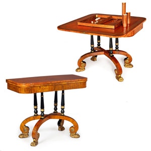 May include: Two antique game tables with intricate wood inlays and black painted legs. The tables have a unique design with curved legs ending in gold paw feet. The larger table has a game board insert.