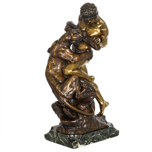 Puede incluir: Una escultura de bronce de un hombre luchando contra una pantera. La escultura está sobre una base de mármol verde.