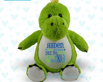 May include: Green plush dinosaur stuffed animal with a white embroidered patch on its chest. The patch includes the name "Ayden", the text "Jon Ashorn", the date "DEC 5th 2018", the time "9:55 PM", the weight "8 pounds 3 oz", and the text "Hope Stitch Embroidery LLC".