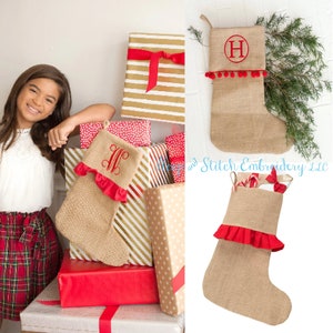 May include: Two burlap Christmas stockings with red ruffles and pom-poms. One stocking is monogrammed with the letter "H" and the other with the letters "LF".
