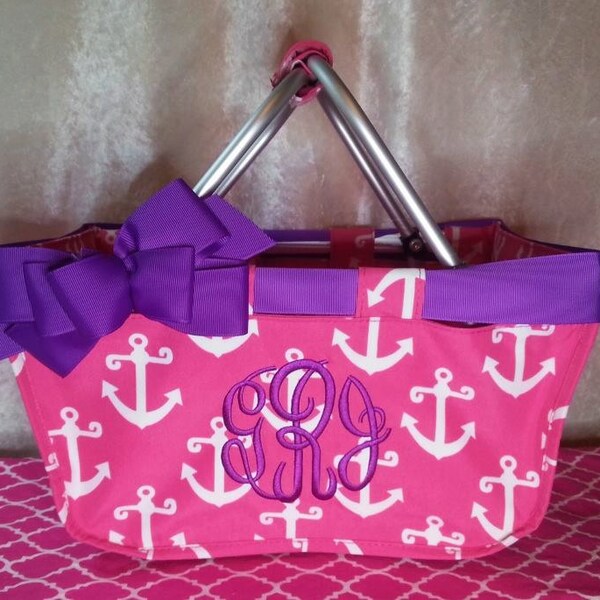 May include: Pink canvas tote bag with white anchor print and a purple bow. The bag has a silver metal handle and a monogrammed initial "C" in purple.
