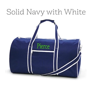 May include: Navy blue duffel bag with white trim and handles. The bag has a zippered main compartment and a shoulder strap. The word "Pierce" is embroidered in green on the front. The text "Solid Navy with White" is above the bag.