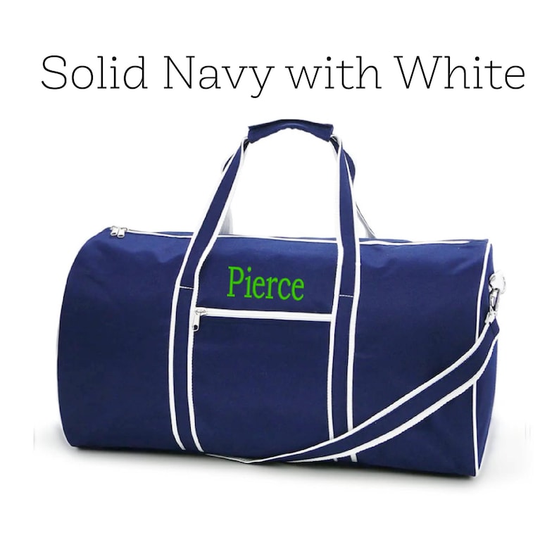 May include: Navy blue duffel bag with white trim and handles. The bag has a zippered main compartment and a shoulder strap. The word "Pierce" is embroidered in green on the front. The text "Solid Navy with White" is above the bag.