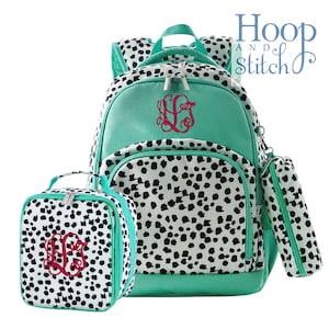 May include: A teal blue backpack, lunch bag, and pencil case set with a black and white dalmatian print. The set is monogrammed with the initials "LLG" in red.