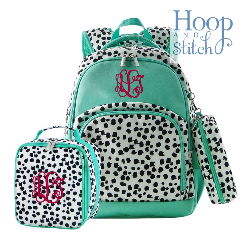 May include: A teal blue backpack, lunch bag, and pencil case set with a black and white dalmatian print. The set is monogrammed with the initials "LLG" in red.
