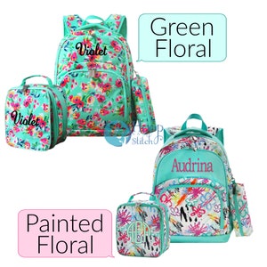 May include: Two sets of personalized backpacks and lunch bags. The first set features a green floral print with the name "Violet" embroidered on the backpack and lunch bag. The second set features a white and green abstract paint splatter design with the name "Audrina" embroidered on the backpack and the initials "AER" on the lunch bag. Both sets include a matching pencil pouch.
