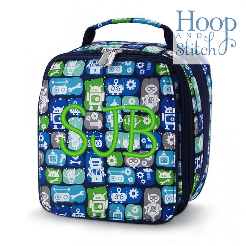 Op de afbeelding: Een blauwe lunchtas met een robotpatroon en de letters "SJB" geborduurd in groen. De tas heeft een ritssluiting en een bovenste handvat.