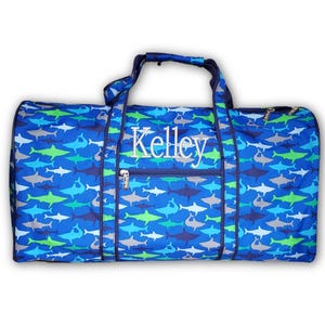 Pu&ograve; includere: Una borsa da viaggio blu con un motivo a squali nei toni del blu, verde e grigio. La borsa ha una tasca frontale con cerniera e manici. Il nome "Kelley" &egrave; ricamato sul davanti.