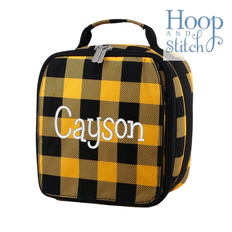 Op de afbeelding: Gele en zwarte geruite lunchtas met een ritssluiting en een handvat. De tas is gepersonaliseerd met de naam "Cayson" in witte borduurwerk.