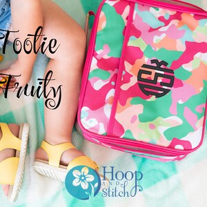 May include: A pink and green camouflage lunch bag with a black monogram. The bag is on a turquoise and white blanket. The text "Tootie Fruity" is written in black cursive on the left side of the image. The text "Hoop and Stitch" is written in black cursive on the right side of the image.