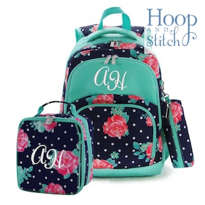 May include: A teal and navy blue floral backpack set with a lunch bag and pencil pouch. The backpack has a large front pocket with a teal zipper and the initials "AJ" embroidered in white. The lunch bag and pencil pouch have the same floral pattern and the initials "AJ" embroidered in white.