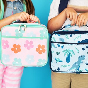 May include: Two lunch bags, one with a pink floral pattern and the other with a blue dinosaur pattern.