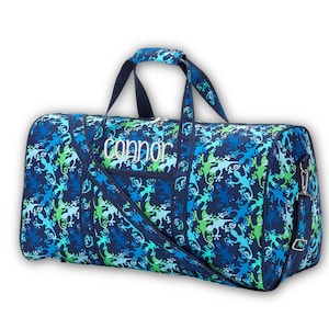 Pu&ograve; includere: Borsa da viaggio blu con un motivo a lucertola nei toni del blu e del verde. La borsa ha un manico superiore, una tracolla e il nome "Connor" ricamato in bianco. La borsa misura circa 61 cm di lunghezza.
