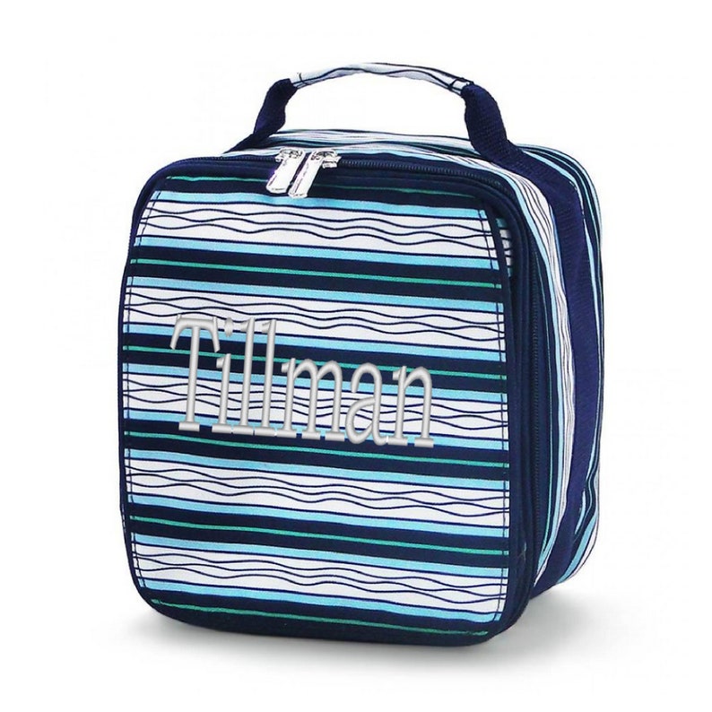 Op de afbeelding: Blauw-witte gestreepte lunchtas met een ritssluiting en een handvat. De tas is gepersonaliseerd met de naam "Tillman" in zilveren borduurwerk.