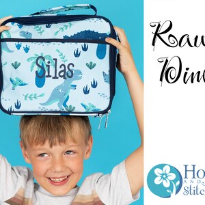 May include: A blue lunch bag with a dinosaur print and the name "Silas" embroidered on it. The bag is being held up by a child. The text "Roar Dino" is written in black cursive on a white background. The logo for "Hoop and Stitch" is in the bottom right corner.