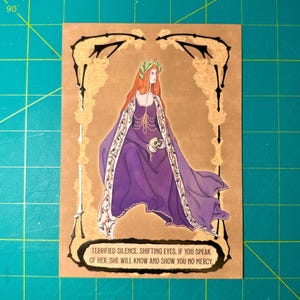 May include: Illustration of a woman in a purple gown and a laurel wreath, holding a skull. The artwork is on a tan background with a decorative border. Text at the bottom reads: "TERRIFIED SILENCE. SHIFTING EYES. IF YOU SPEAK OF HER, SHE WILL KNOW AND SHOW YOU NO MERCY."