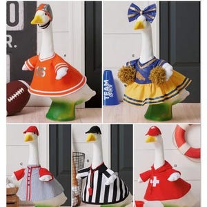 May include: A Simplicity S3298 sewing pattern envelope featuring five white goose figurines dressed in various outfits: a football player with an orange jersey, a cheerleader with a blue and yellow dress, a baseball player, a referee, and a lifeguard.