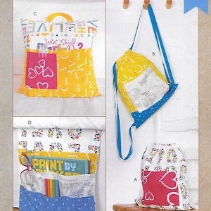 May include: Sewing pattern for three different projects: a yellow and blue drawstring backpack, a yellow and pink reading pillow, and a blue and white bed organizer. The pattern is called "kwik sew" and the number is K4319.
