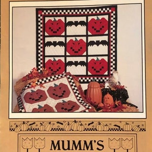 May include: A quilt pattern for a Halloween quilt featuring a pumpkin patch design. The pattern includes instructions for making a quilt with a patchwork of pumpkins and bats. The quilt is made with red, black, white, and green fabric. The pattern is titled "The Pumpkin Patch" and is from "Mumm's The Word".