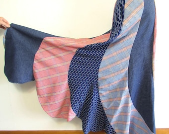 May include: A long, flowing skirt with a patchwork design. The skirt features panels of denim blue, pink and white striped fabric, and navy blue patterned fabric. The skirt is displayed on a mannequin.