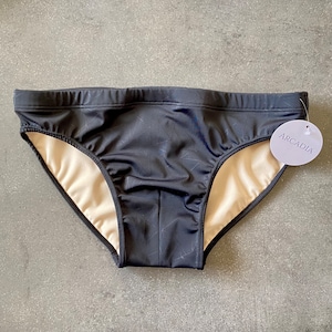 May include: Black swim trunks with a geometric pattern and a white tag that says "ARCADIA".