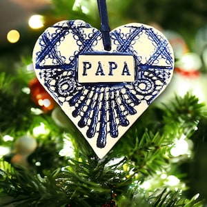 May include: White ceramic heart ornament with blue lace design and a white tag that says "PAPA".
