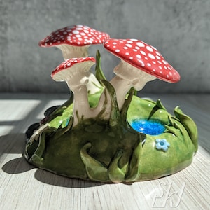 Scultura di funghi e rospi con una pozzanghera di erba d&#39;acqua e piccoli fiori Collina