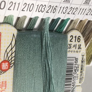 May include: A spool of light green embroidery floss with a label that reads "216 深川鼠 - かがわねず" and a barcode. The label also includes the text "LOT 4E6C" and "大黑絲業株式会社".