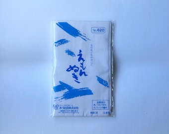 May include: A rectangular white fabric accessory in clear plastic packaging, featuring blue brushstroke patterns and Japanese text. The label includes the text No. 620, Japanese characters, and a small logo at the bottom left corner.