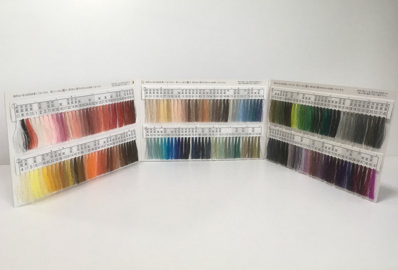 May include: A color chart with rows of thread samples in various colors, including red, orange, yellow, green, blue, purple, and brown. The chart is divided into sections with numbers and Japanese text.