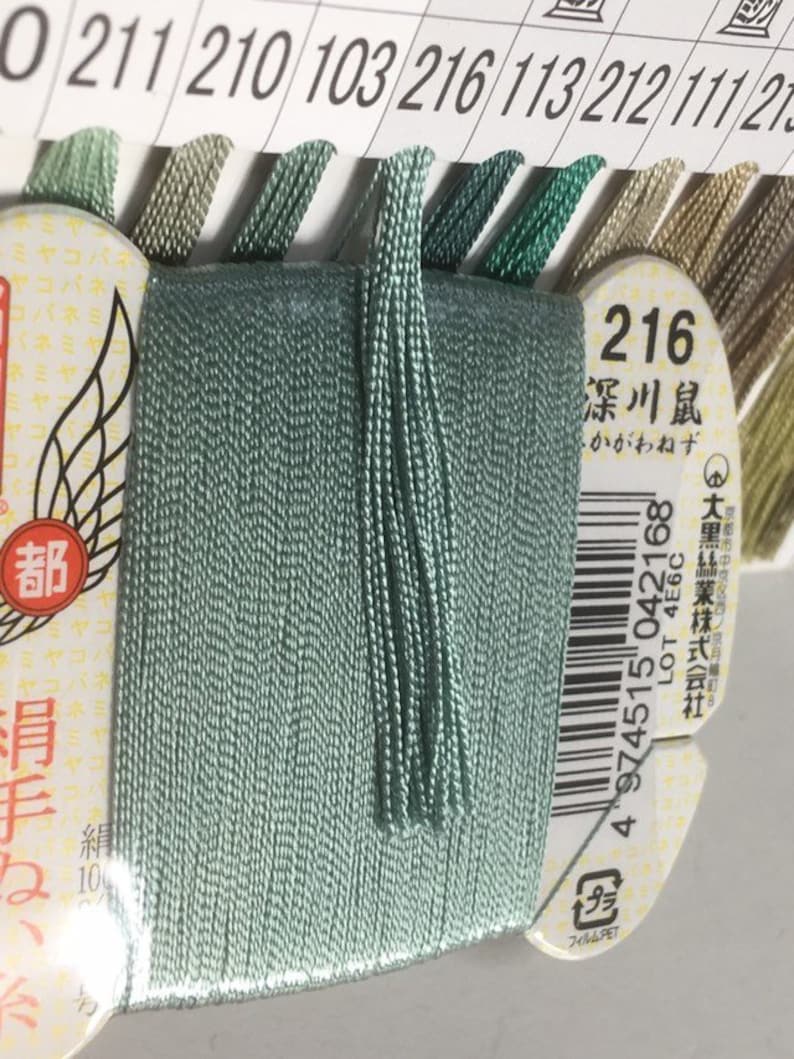 May include: A spool of light green embroidery floss with a label that reads "216 深川鼠 - かがわねず" and a barcode. The label also includes the text "LOT 4E6C" and "大黑絲業株式会社".