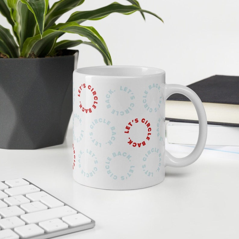 White workplace buzzword coffee mug with text that reads "let's circle back" in pale blue and bright red