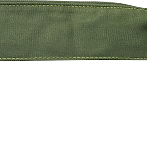 May include: Olive green belt bag with a rectangular main compartment and a small zippered pouch. The bag features a gold-colored metal zipper and a circular metal ring. The bag is made of a durable fabric and is designed to be worn around the waist.