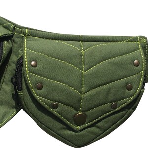 May include: Olive green fanny pack with leaf-shaped pockets and decorative stitching. The pack features a zippered pocket, metal rivets, and a circular metal buckle. The belt is adjustable.