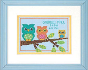 May include: A cross-stitch pattern featuring three owls on a branch with green, orange, and yellow accents. The text "Gabriel Paul 3-1-2018 8 lb 7 oz" is stitched below the owls.