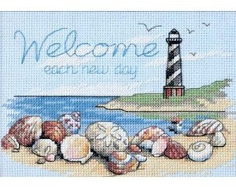 May include: Cross stitch pattern featuring a lighthouse on a beach with seashells and the text "Welcome each new day".